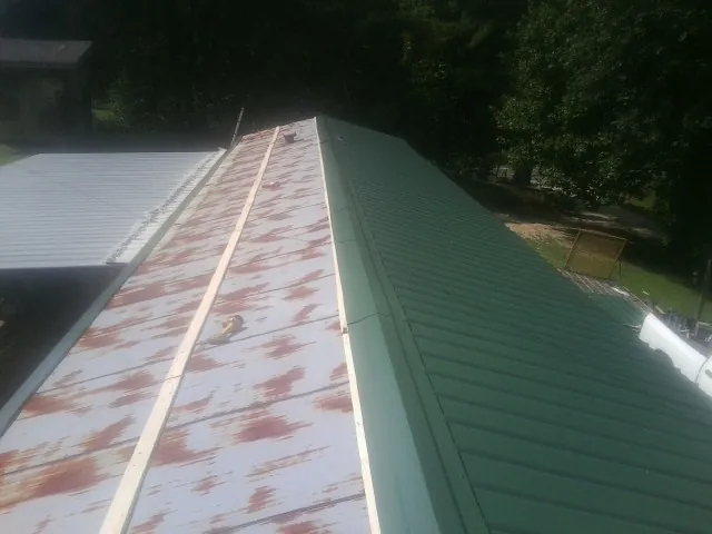 Old rusted panels beside newly installed green metal roofing — Wind Damage Roof Repair by Roofing Brothers in Salida