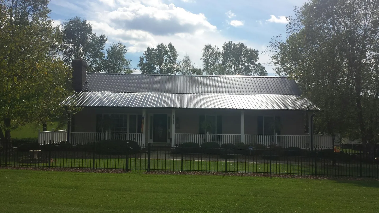 Gray metal roof on a brick ranch with a full width front porch — Gutter Guard Installation work by our crew in Salida