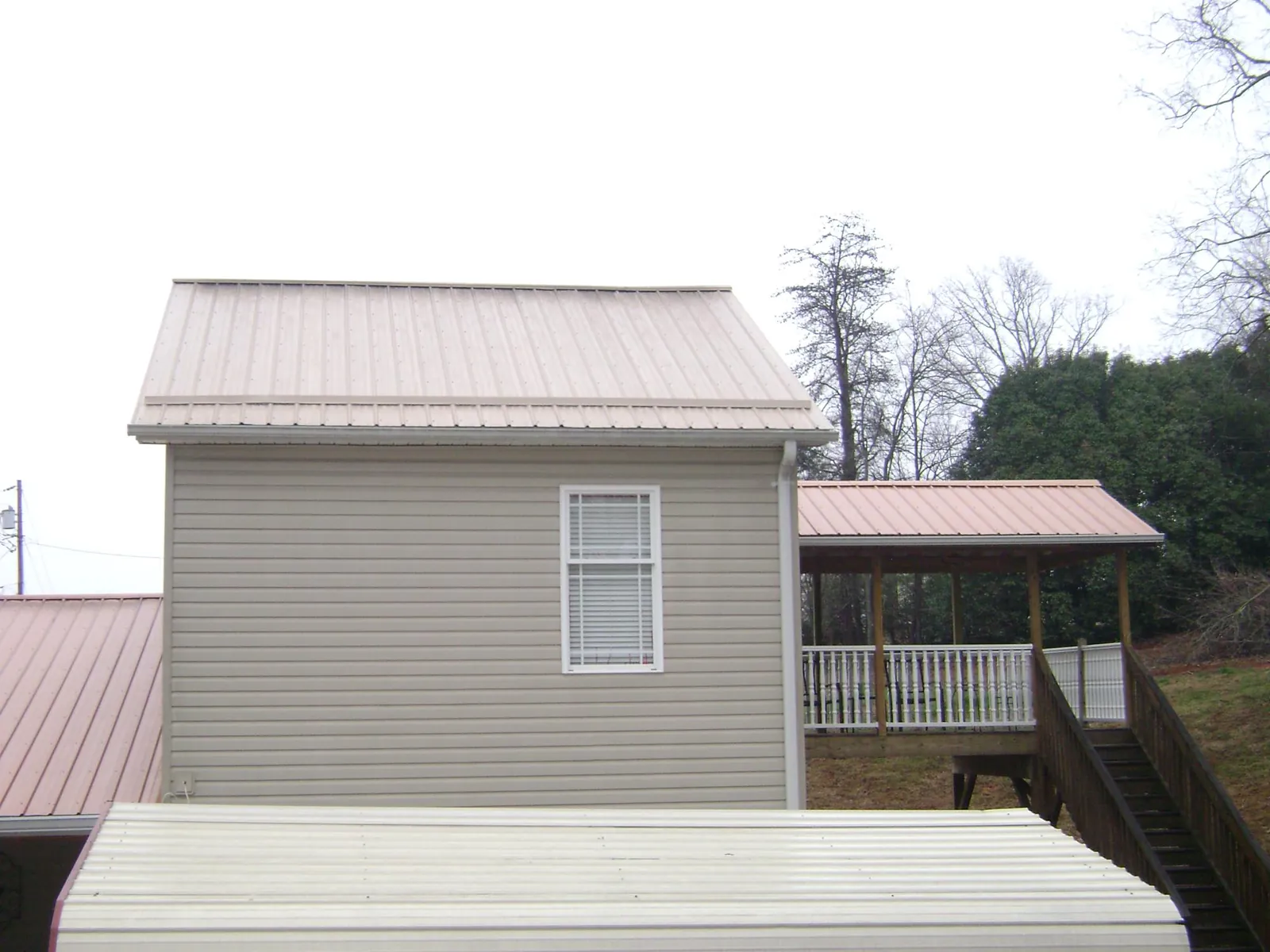 Tan metal roofs on a two story addition and attached porch, from a Roof Replacement job in Salida